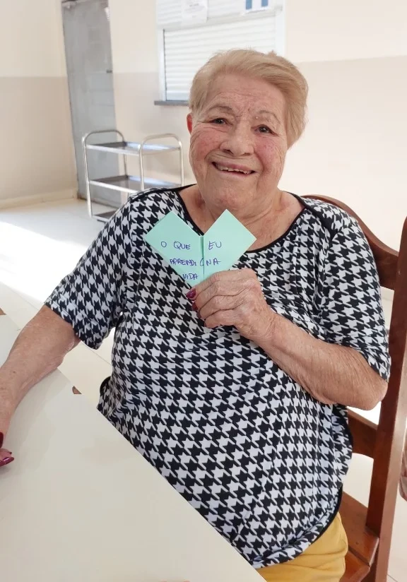 Dona Maria Apparecida segurando coração de origami com lições de vida